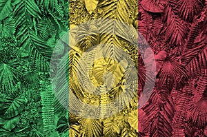 Mali flag depicted on many leafs of monstera palm trees. Trendy fashionable backdrop