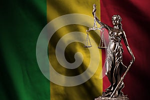 Mali flag with statue of lady justice and judicial scales in dark room. Concept of judgement and punishment