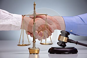 Gavel In Front Of Two Men Shaking Hands