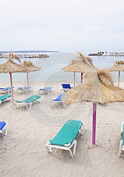 Parasols and sun lounges on Cala Estancia beach before rain.