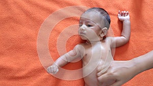 Malnourished baby looking at the camera lying on orange red velvet cloth background. protein energy malnutrition concept