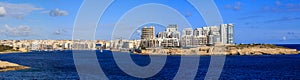 Malta, Valletta. Sliema town with multistorey buildings, blue sea and blue sky with few clouds background. Panoramic view, banner. photo