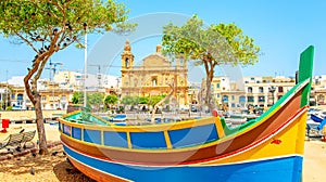 Maltese traditional colorful boat and Msida Parish Church on background, Malta