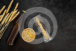 Malting barley near beer bottle and glass on black background top view copyspace