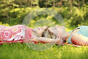 Mama and her little daughter lie on the grass