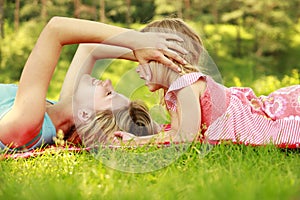 Mama and her little daughter lie on the grass