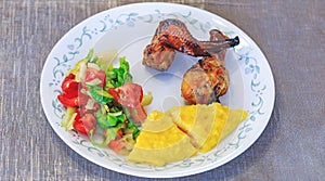 Mamaliga or polenta, baked chicken legs and salad in fancy plate. Traditional food and culinary culture specific for Balkan