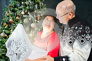 Man 60s giving a Christmas present to his woman. Opening gift box at christmas time. Christmas wonder concept
