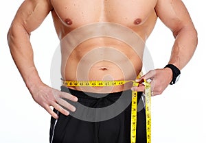 Man abdomen with measuring tape over blue background.