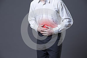 Man with abdominal pain, stomach ache on gray background photo