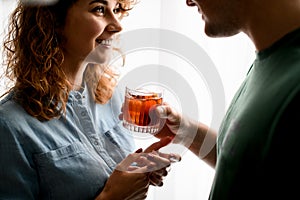 Man accurate holds out glass with cocktail to young beautiful woman.