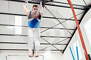 Man, acrobat and gymnastics balance on rings in fitness for practice, training or workout at gym. Professional male