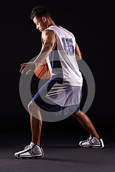 Man, action and basketball in studio for fitness, competition and sports player on black background. Professional