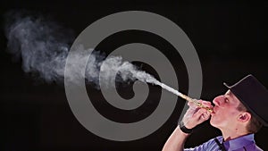 The man the actor blows a gray smoke from a tube. Soap bubbles show.