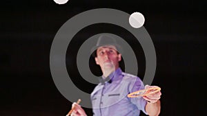 The man the actor blows two soap bubbles with a gray smoke and plays with them in tennis. Soap bubbles show.