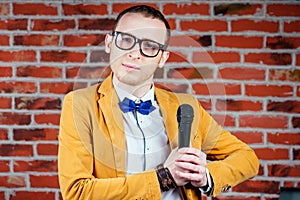 A man actor comedian in glasses, a stylish and tie suit holds a microphone. concept of public speaking