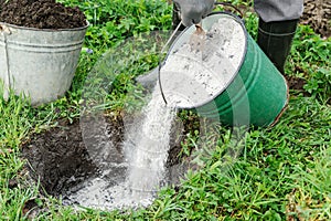 Man is adding a ashes into a pit.