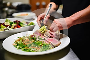 a man adding a side salad to his sesame tuna steak dish
