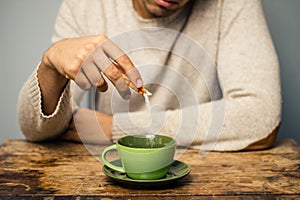 Man adding sugar to his coffee or tea