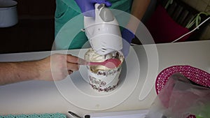 A man adds stewpan syrup to a container. Woman using a blender mixes marshmallow and syrup in a container