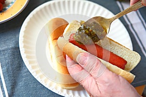 Putting pickle relish on hot dog