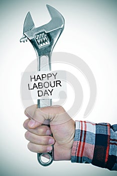 Man with adjustable wrench and signboard with text happy labour