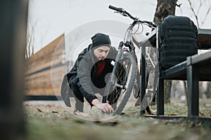 Man adjusting bicycle chain in a park at sunset, embracing outdoor fitness