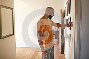 Man Adjusting Digital Central Heating Thermostat At Home