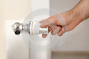 Man adjusting heating radiator thermostat