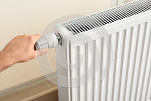 Man adjusting heating radiator thermostat