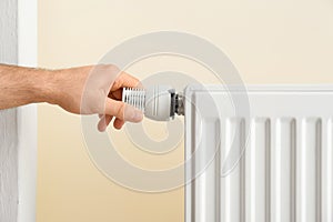 Man adjusting heating radiator thermostat