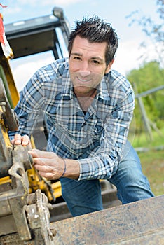 Man adjusting linkage on digger bucket