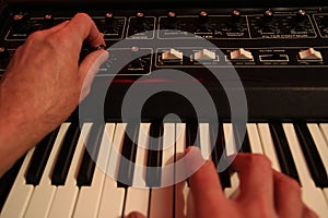 Man adjusting and playing vintafge analogue music synthesizer