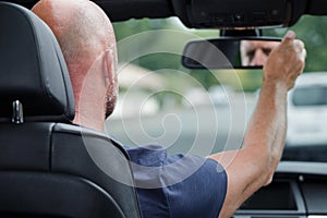 Man adjusting rear-view mirror inside car