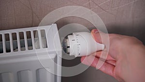 Man adjusting temperature on heating radiator, energy crisis concept. Selective focus