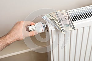 Man adjusting temperature of heating radiator with money