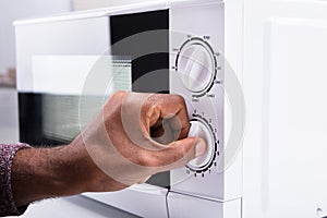 Man Adjusting Temperature Of Microwave Oven