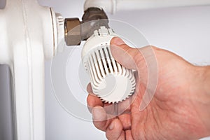 Man adjusting temperature on radiator thermostat