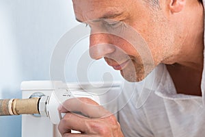 Man adjusting temperature of radiator thermostat