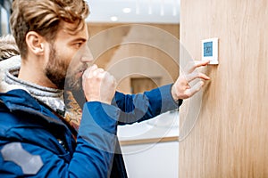 Man adjusting temperature with thermostat at home