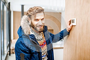 Man adjusting temperature with thermostat at home