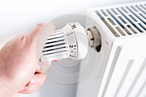 Man adjusting temperature on thermostat on radiator