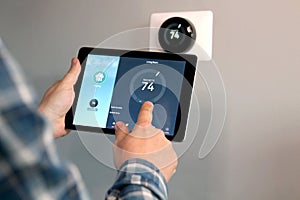 Man is Adjusting a temperature using a tablet with smart home app in modern living room