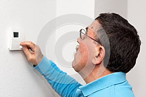Man adjusting thermostat at home, focus on face. Celsius temperature scale.
