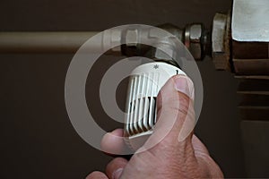 Man adjusting thermostatic radiator valve, controlling central heating temperature