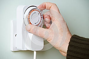 Man Adjusting Timer On Electrical Socket