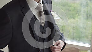 Man adjusts the lapels of his suit jacket