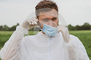 A man adjusts a mask on his face in the outdoors. Quarantine, world pandemic, COVID-19