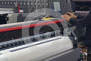 A man adjusts the printing process on a large format printing machine