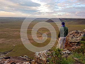 A man admiring a sunrise from a small hill in the suburbs of Xilinhot, Inner Mongolia. The sky is painted in orange, red